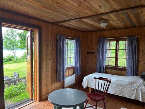 a bedroom with a bed and a table and two windows at Lommen in Dals Långed