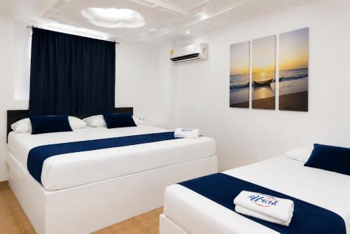 a bedroom with two beds and a painting on the wall at Hotel Urak in Valledupar