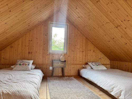 two beds in a wooden room with a window at Domek BrzozoweLove in Szczodrowo