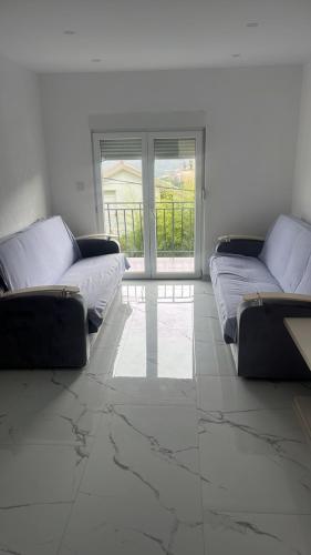 a living room with two couches in front of a window at Apartmani Rubi 2 in Herceg-Novi