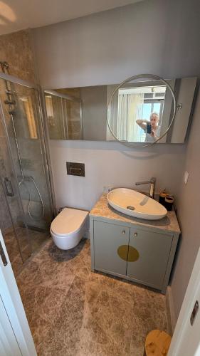 a man taking a picture of a bathroom with a toilet and a sink at Beachfront Villa with private beach and pool in Bogazici