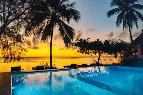 a swimming pool with a sunset in the background at Mnana Beach Bungalows in Michamvi