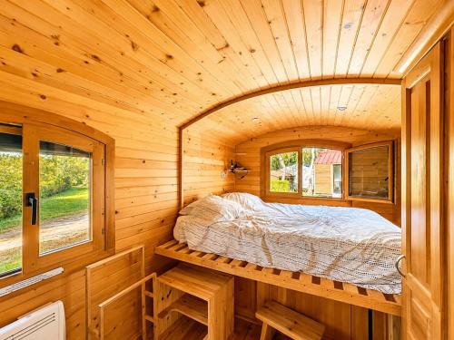 a bedroom in a wooden cabin with a bed in it at Blue : La Roulotte du Médoc in Naujac-sur-Mer