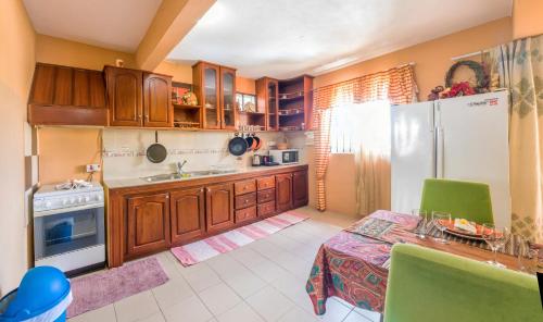 a kitchen with wooden cabinets and a table and a refrigerator at Sunset Villa in La Gaulette