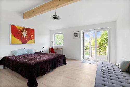 a white bedroom with a bed and a sliding glass door at 1695-Hundested-Valdemar-Poulsensvej-11 in Lynæs