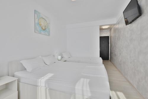 a white room with a bed and a tv at Neptune Breeze in Neptun