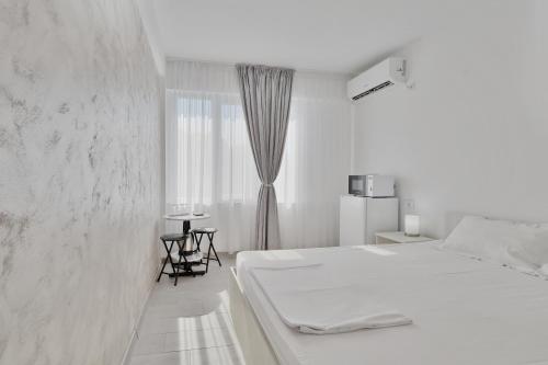 a white bedroom with a bed and a window at Neptune Breeze in Neptun