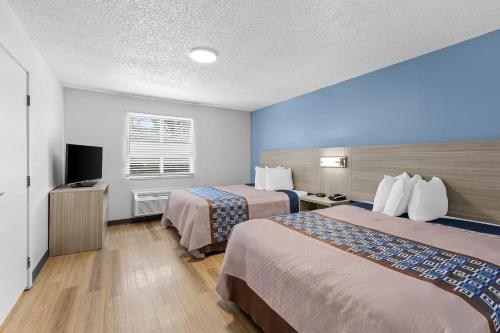 a hotel room with two beds and a flat screen tv at Suburban Studios Copley Akron West in Copley