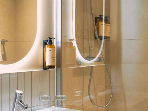 a bathroom with a shower with two bottles of soap at Mercure Pont d’Avignon Centre in Avignon
