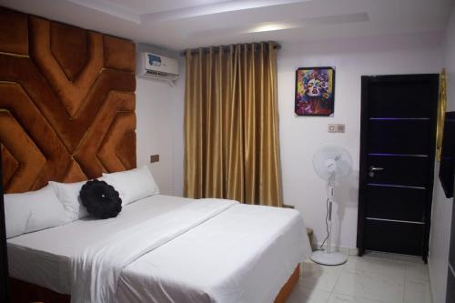 a bedroom with a white bed with a wooden headboard at Star Haven Hotel and suites in Badore