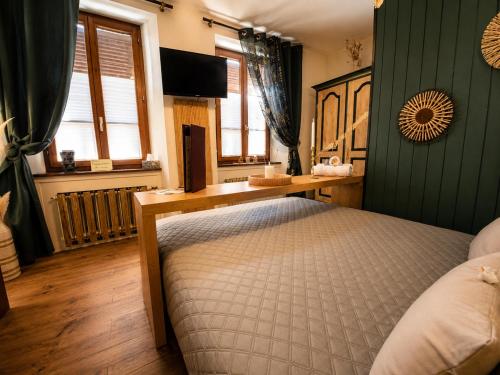 a bedroom with a bed and a desk and windows at Hôtel de la Couronne in Les Bois