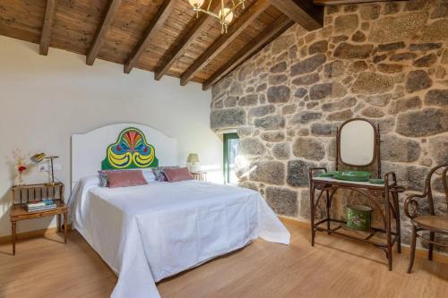 a bedroom with a bed in a stone wall at Casa do Capitán in Leiro