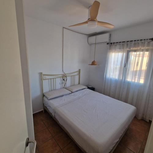 a bedroom with a white bed and a ceiling fan at Picasso Beach House in Oliva