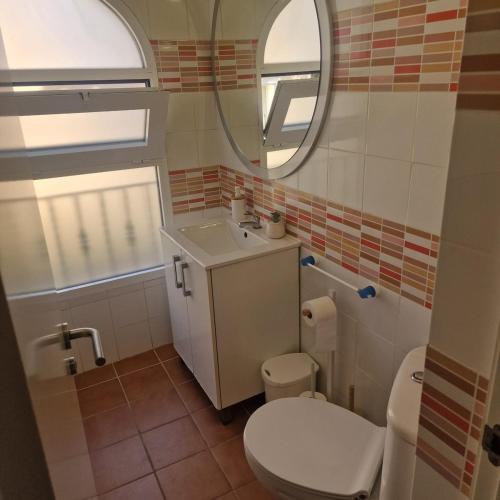 a bathroom with a toilet and a sink and a mirror at Picasso Beach House in Oliva