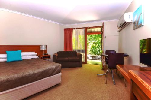 a hotel room with a bed and a chair and a desk at River Country Inn in Moama
