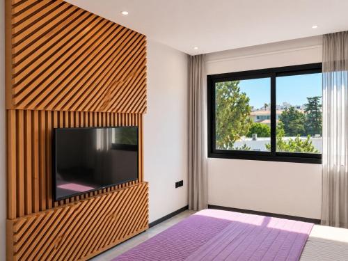 a bedroom with a flat screen tv and a large window at Kay-Stay in Larnaca