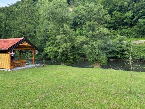 a gazebo in a field next to a river at River Resort Vinac Jajce in Jajce