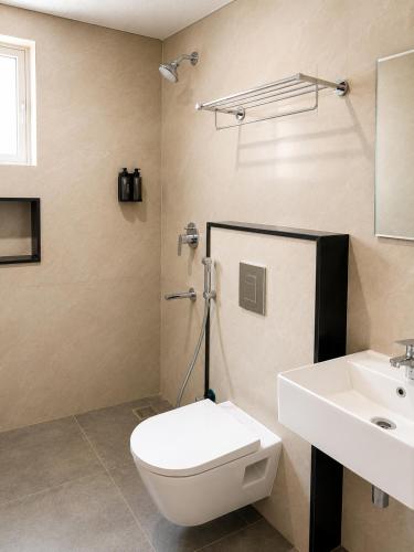 a bathroom with a white toilet and a sink at Parthas Suites in Tiruchirappalli