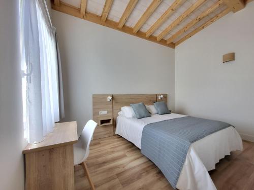 a bedroom with a bed and a desk and a chair at Apartamentos Las Terrazas de Suances in Suances