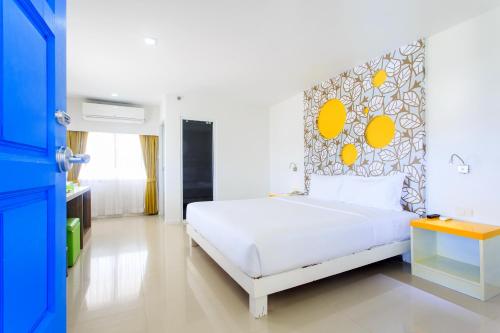 a bedroom with a white bed with a yellow headboard at Samui Verticolor in Chaweng