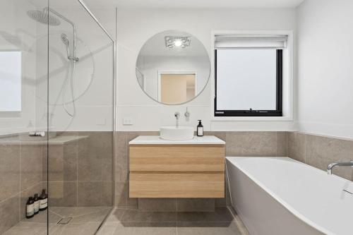 a bathroom with a tub and a sink and a mirror at Modern Lindisfarne Escape in Lindisfarne