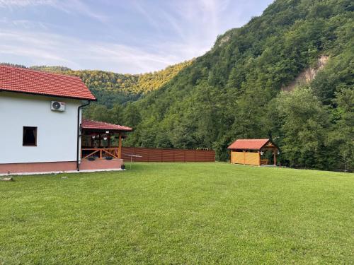 a large yard with a building and a mountain at River Resort Vinac Jajce in Jajce
