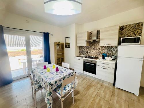 a kitchen with a table with chairs and a refrigerator at Appartamenti Abbaidda in Valledoria
