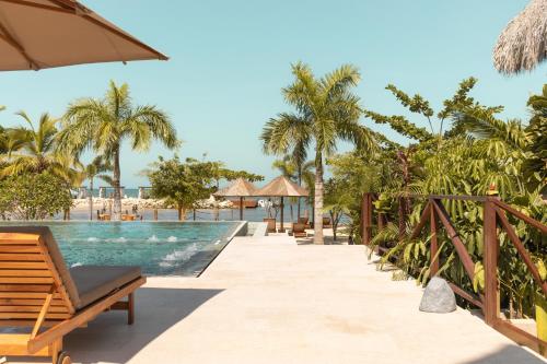 ein Pool in einem Resort mit Bänken und Palmen in der Unterkunft Hotel Aimarawa in Coveñas