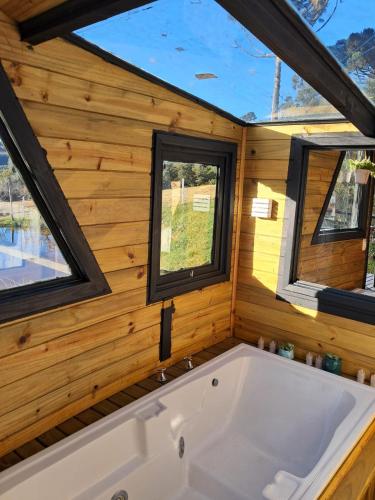a tub in a tiny house with two windows at Vale do Sossego- Cabana na Serra in Alfredo Wagner