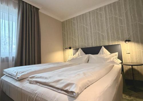 ein großes weißes Bett in einem Zimmer mit Fenster in der Unterkunft Olymp Munich in Eching