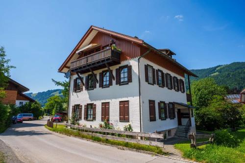 a white house with a wooden roof on a street at Direkt am Wanderweg, Ferienwohnung im Allgäu nahe Oberstaufen in Oberstaufen