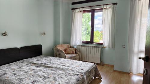 a bedroom with a bed and a chair and a window at Premium Villa Tode in Bansko