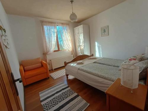 a bedroom with a bed and a chair in it at къща Утринна Роса in Blŭskovtsi