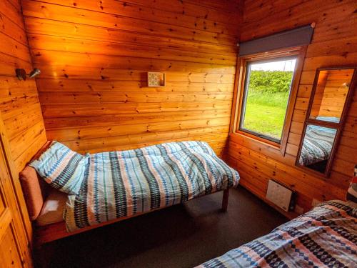 a bedroom of a log cabin with a bed and a window at Avallon Lodges in Launceston