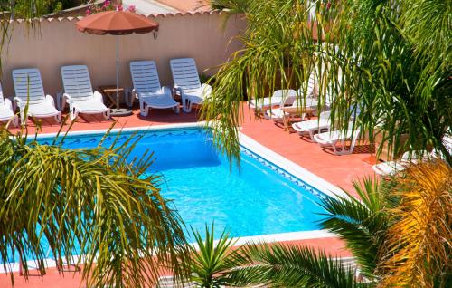 uma piscina com cadeiras e guarda-sóis e palmeiras em Argentiere-Club em La Londe-les-Maures