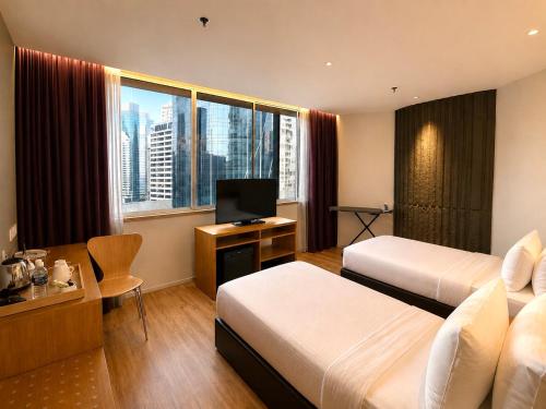 a hotel room with two beds and a television at deKing Hotel Twin Towers by DK Hospitality in Kuala Lumpur
