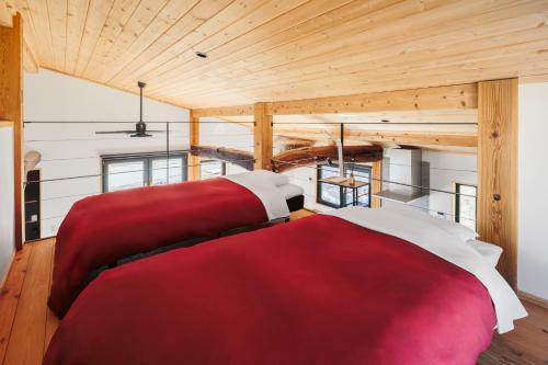 a bedroom with a red and white bed and wooden ceilings at New Field Chalet 白馬 in Hakuba