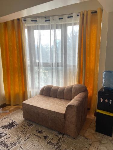 a living room with a couch in front of a window at Pendo suite in Nairobi