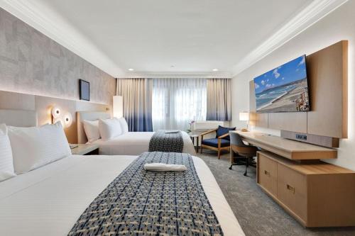 a hotel room with two beds and a desk at Best Western Plus Sunset Plaza Hotel in Los Angeles