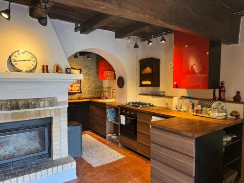 a kitchen with a fireplace and a clock on the wall at Il Rifugio - Cottage With Pool in Toano