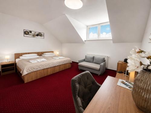 a bedroom with a bed and a chair and a table at Hotel Evan u Hoffera with free parking in Topoľčany