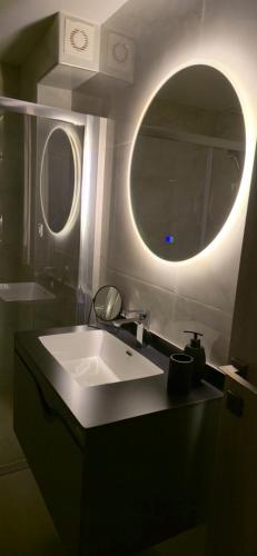 a bathroom with a sink and a round mirror at Kos Cozy Home in Platánion