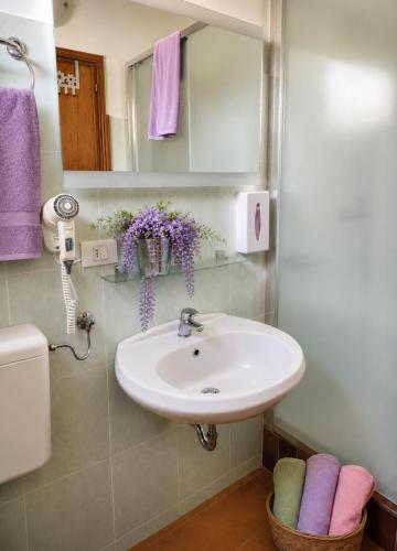 a bathroom with a sink and a mirror and purple towels at Casa Augusta in Maccagno Superiore