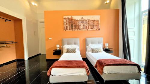 two beds in a room with an orange wall at Palazzo Goyze in Naples