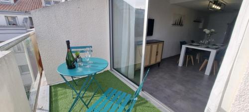 a small blue table with a wine glass on a balcony at L'Ophelia Duplex Dernier étage balcon Centre climatisation in Sète
