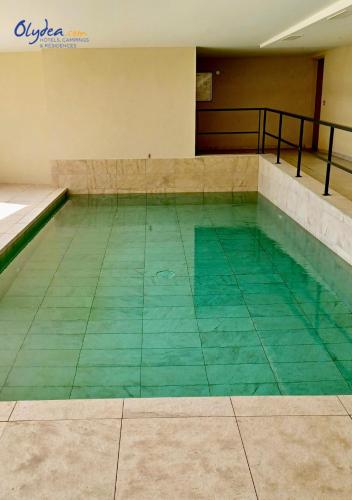 a swimming pool with green water in a building at Olydea Beausoleil in Beausoleil
