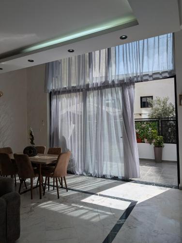 a dining room with a table and chairs and a large window at Tanger City 6 in Tangier