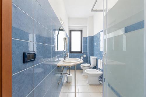 a blue tiled bathroom with a sink and a toilet at Oasi Park Hotel in Mascali