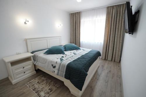 a bedroom with a bed with blue pillows and a television at Apartament Ultracentral NICOL in Curtea de Argeş