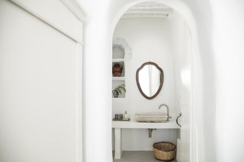 a white bathroom with a mirror and a sink at DYO Tinos in Triandáros
